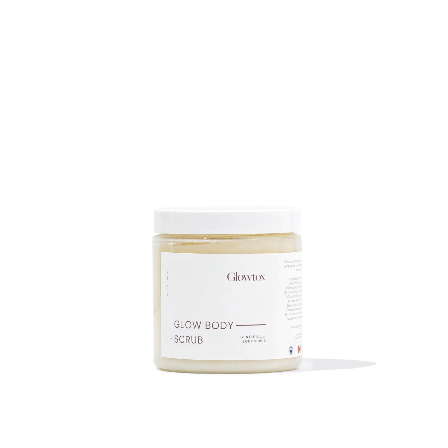 A jar of Glowtox Glow Body Scrub featuring a minimalist design, labeled as a gentle sugar body scrub, with a light golden scrub inside.
