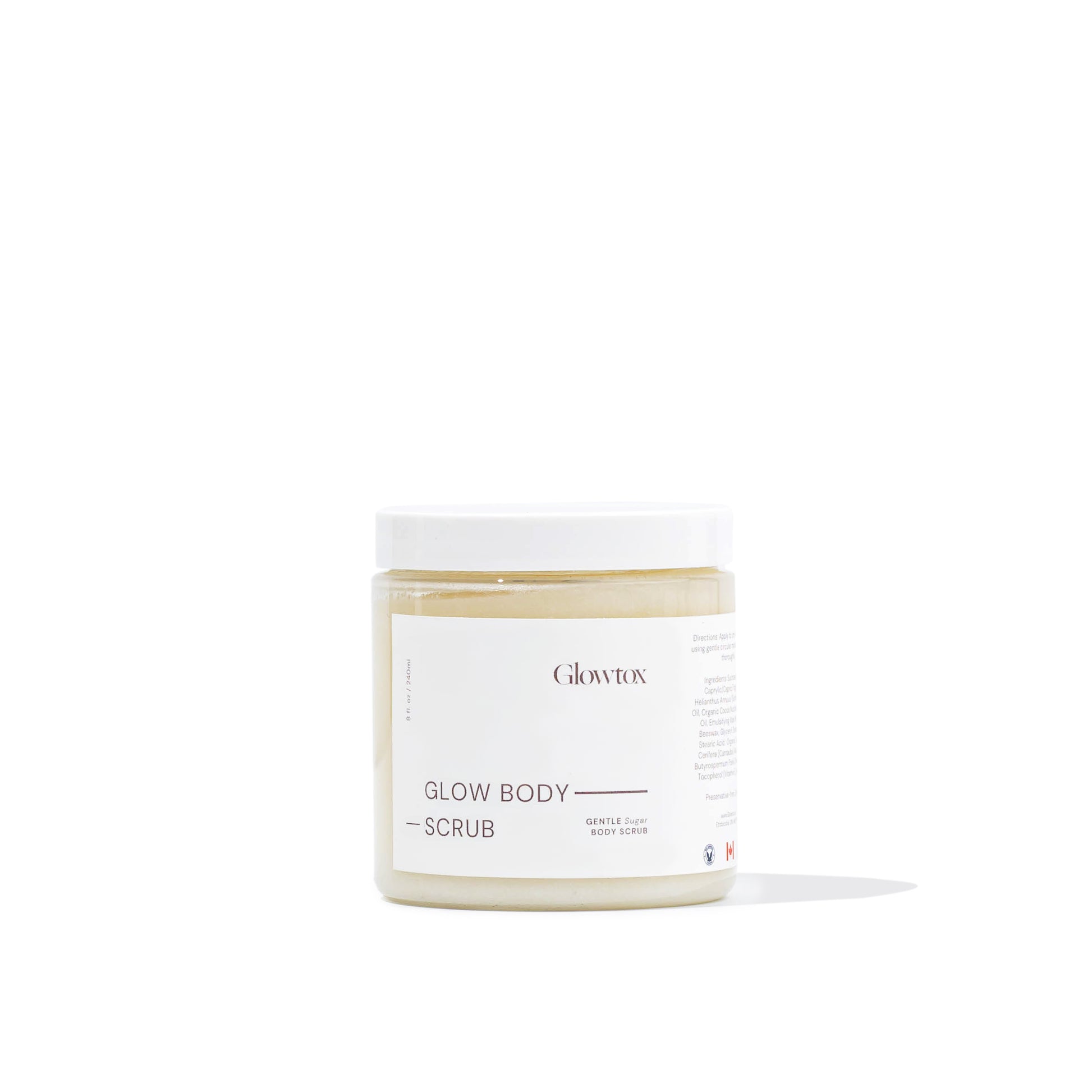A jar of Glowtox Glow Body Scrub featuring a minimalist design, labeled as a gentle sugar body scrub, with a light golden scrub inside.